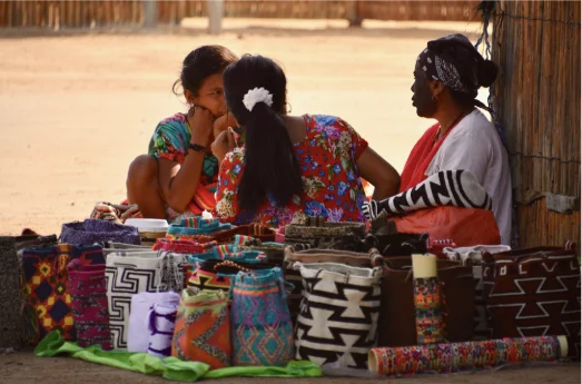 Mujeres wayuu tejiendo y vendiendo mochilas